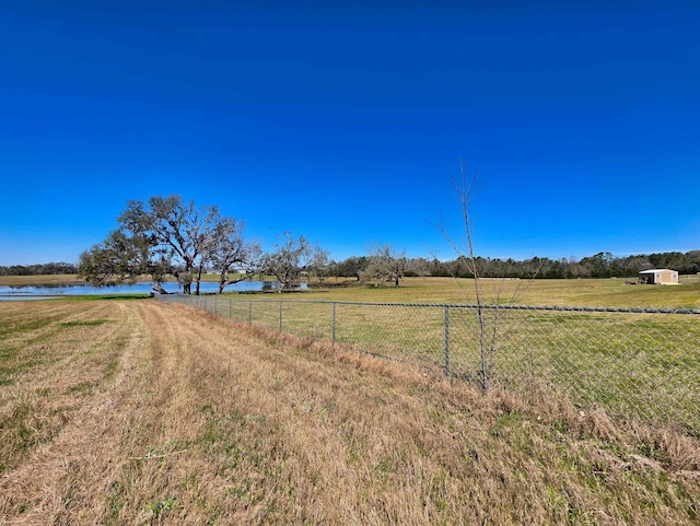 view of yard featuring a rural view, a water view, and fence