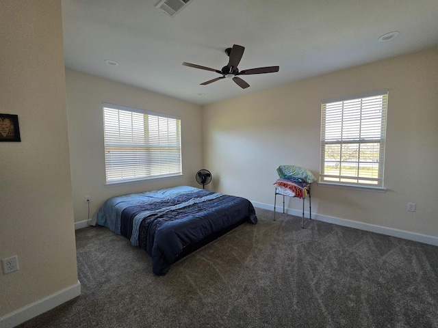 carpeted bedroom featuring a ceiling fan, multiple windows, visible vents, and baseboards