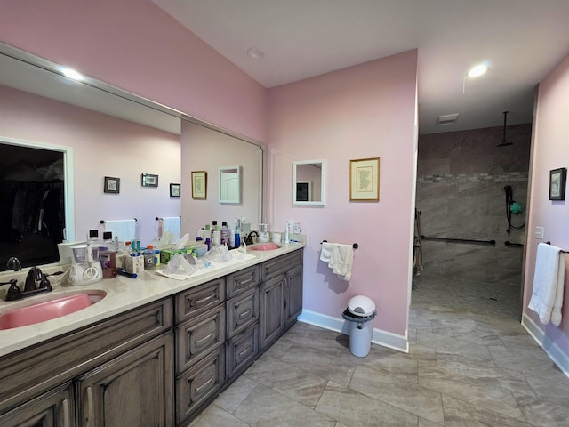 full bath with a walk in shower, double vanity, a sink, and baseboards