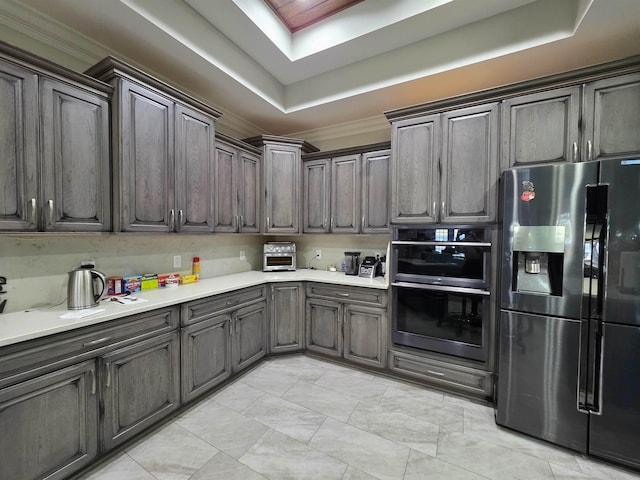 kitchen with a raised ceiling, stainless steel appliances, light countertops, and a toaster