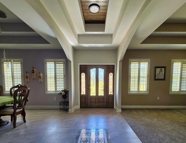 foyer entrance with a raised ceiling and baseboards