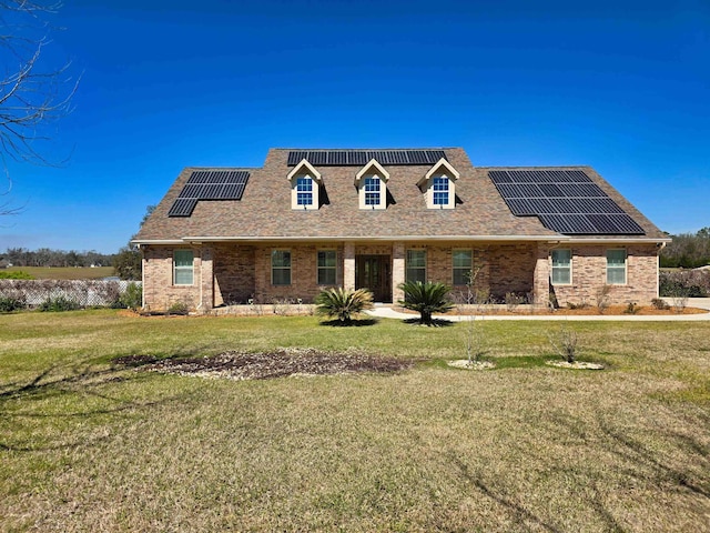 cape cod house featuring brick siding, roof with shingles, roof mounted solar panels, and a front yard