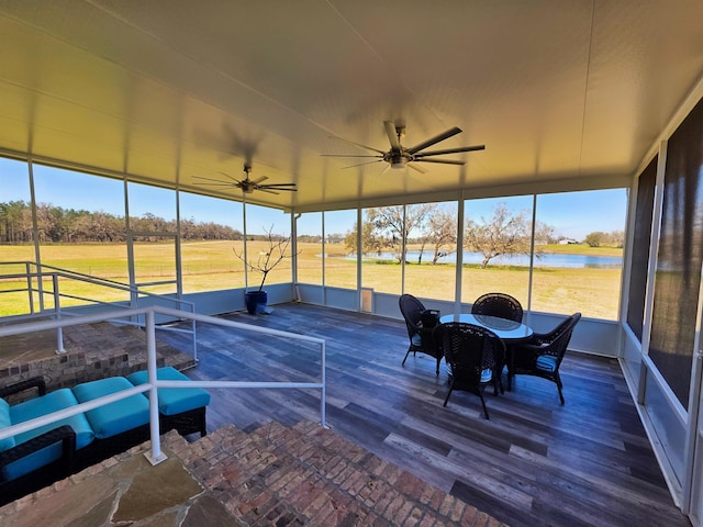 sunroom / solarium featuring a water view and a ceiling fan