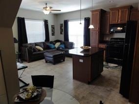 kitchen featuring ceiling fan, hanging light fixtures, black appliances, and a center island