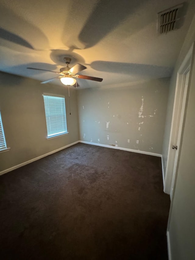 spare room with dark carpet, ceiling fan, and a textured ceiling