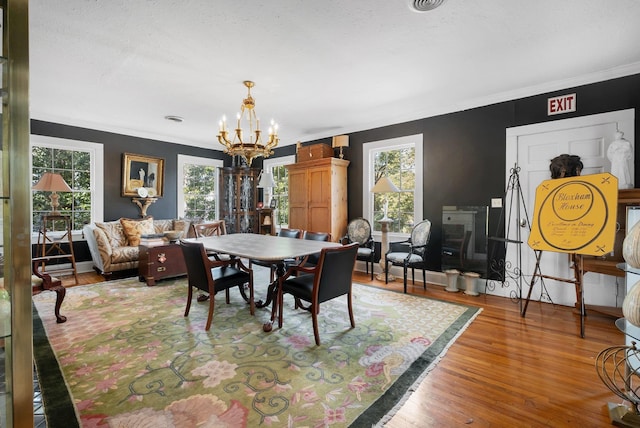 dining area with hardwood / wood-style flooring, ornamental molding, and a notable chandelier