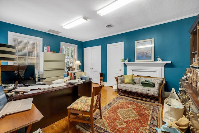 office featuring wood-type flooring, ornamental molding, and a textured ceiling