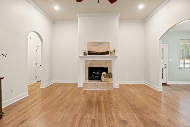 1652 Eagles Watch Way, Tallahassee, FL 32312 - unfurnished living room with ceiling fan, light wood-style flooring, arched walkways, crown molding, and a tile fireplace