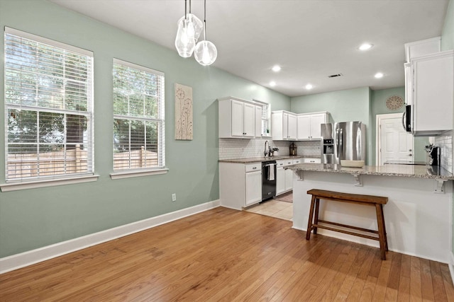 1652 Eagles Watch Way, Tallahassee, FL 32312 - kitchen featuring stainless steel fridge, black dishwasher, decorative backsplash, a peninsula, and light stone counters