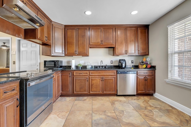 2386 Vega Dr, Tallahassee, FL 32303 - kitchen with under cabinet range hood, a sink, dark stone counters, baseboards, and appliances with stainless steel finishes