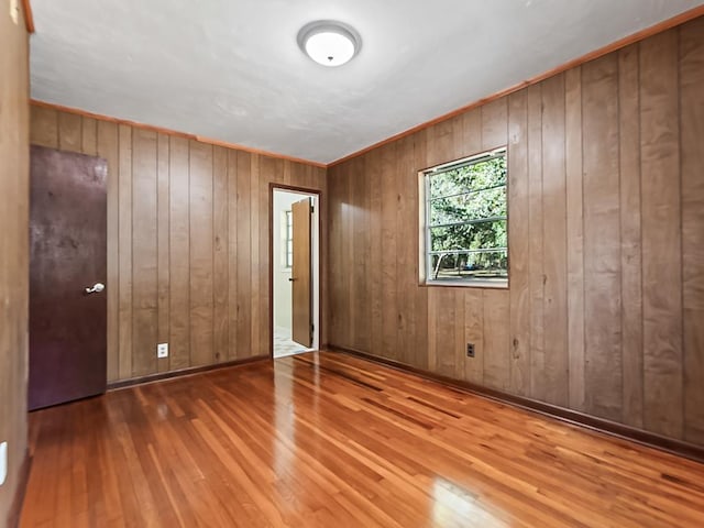 unfurnished bedroom featuring hardwood / wood-style floors and wood walls