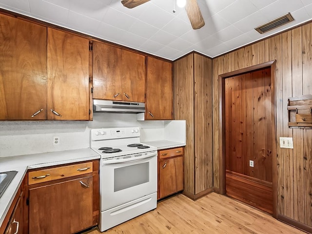 kitchen featuring ceiling fan, wood walls, white electric range, and light hardwood / wood-style flooring