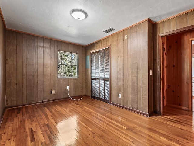 spare room featuring light hardwood / wood-style flooring and wood walls