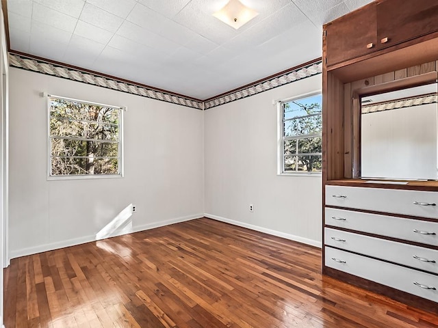 unfurnished bedroom with dark hardwood / wood-style floors and multiple windows