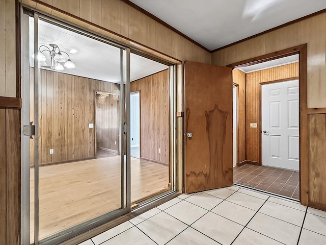 entryway featuring light tile patterned flooring, crown molding, a notable chandelier, and wood walls