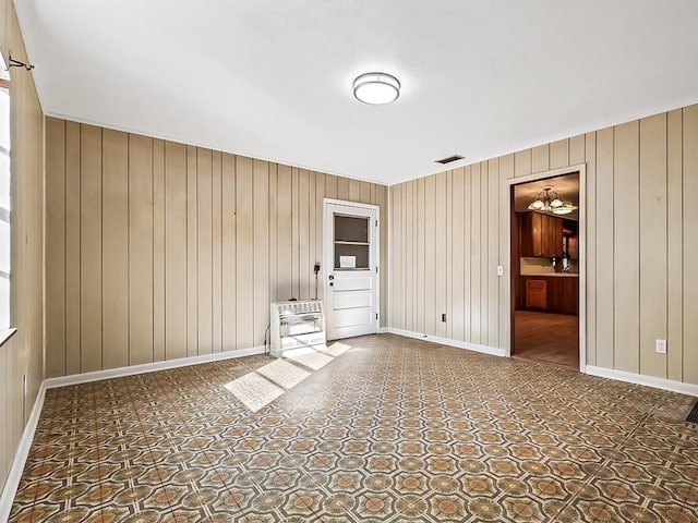 empty room featuring wood walls, carpet floors, and a notable chandelier