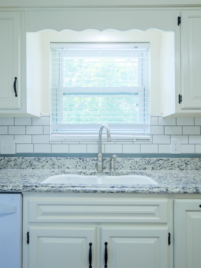 405 NW Whispering Pines Loop, Madison, FL 32340 - detailed view of white cabinetry, backsplash, white dishwasher, and light stone countertops