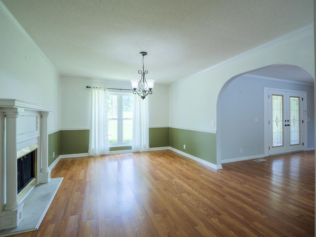 405 NW Whispering Pines Loop, Madison, FL 32340 - unfurnished living room featuring arched walkways, a chandelier, healthy amount of natural light, ornamental molding, and wood finished floors
