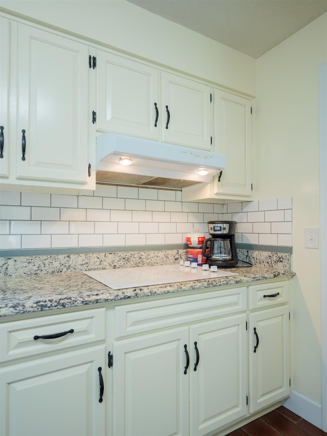 405 NW Whispering Pines Loop, Madison, FL 32340 - kitchen with under cabinet range hood, backsplash, white cabinetry, and light stone countertops