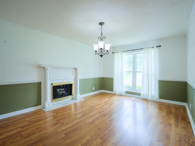 405 NW Whispering Pines Loop, Madison, FL 32340 - unfurnished living room featuring a chandelier, wood finished floors, a glass covered fireplace, ornamental molding, and a textured ceiling