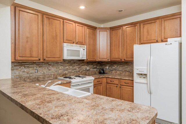 kitchen with sink, kitchen peninsula, tasteful backsplash, light stone countertops, and white appliances