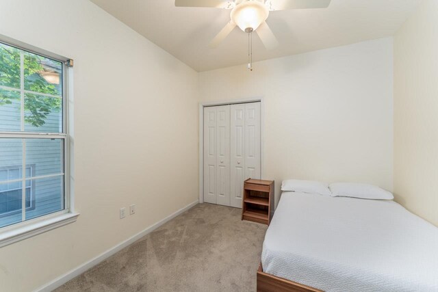 carpeted bedroom with ceiling fan and a closet