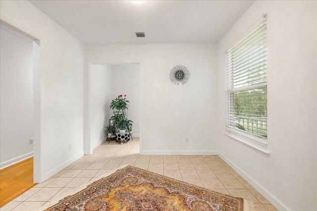 unfurnished room with light tile patterned floors, visible vents, and baseboards