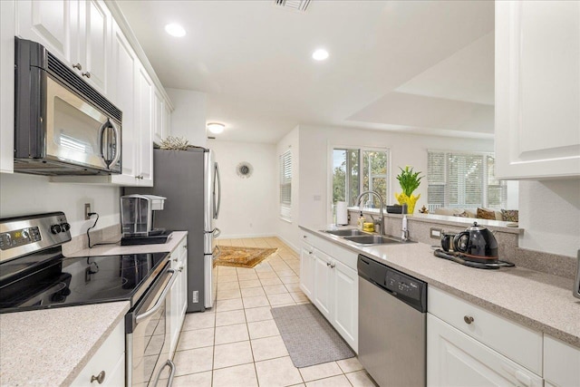 kitchen featuring light tile patterned floors, a sink, light countertops, white cabinetry, and stainless steel appliances