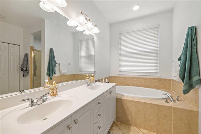 bathroom with tile patterned floors, double vanity, a garden tub, and a sink
