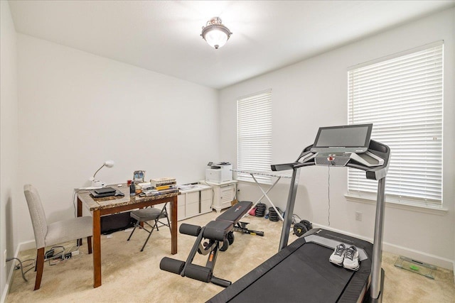 exercise room with light colored carpet and baseboards