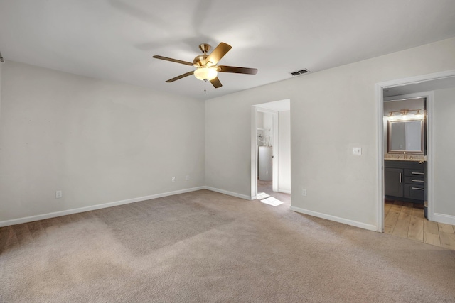 unfurnished bedroom featuring connected bathroom, sink, ceiling fan, and carpet flooring