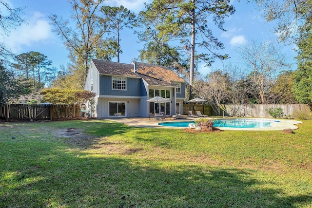 rear view of property featuring a fenced in pool, a patio area, and a lawn