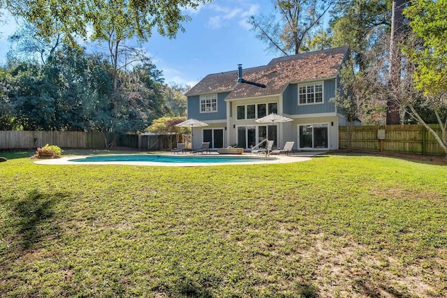 rear view of property with a fenced in pool, a lawn, and a patio area