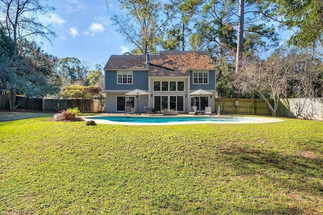 back of property featuring a fenced in pool, a patio, and a lawn