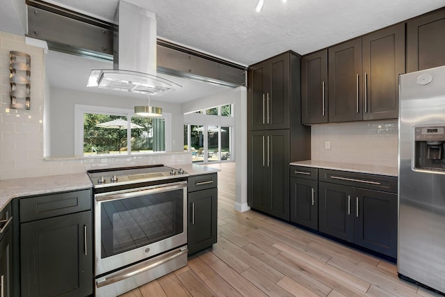 kitchen with decorative backsplash, light stone counters, stainless steel appliances, a textured ceiling, and light hardwood / wood-style flooring