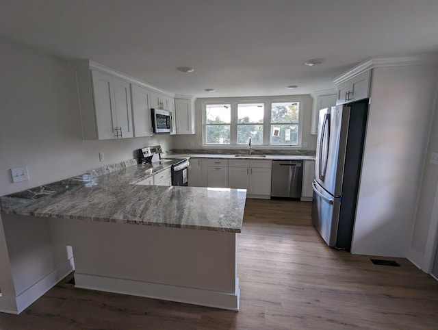 kitchen featuring light stone countertops, appliances with stainless steel finishes, white cabinets, and kitchen peninsula