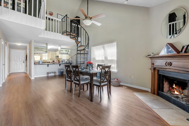 dining room featuring hardwood / wood-style flooring, ceiling fan, and a high ceiling