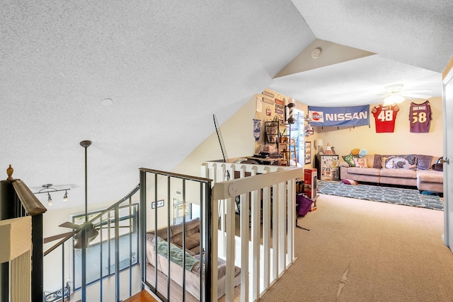 stairs with ceiling fan, carpet floors, a textured ceiling, and lofted ceiling