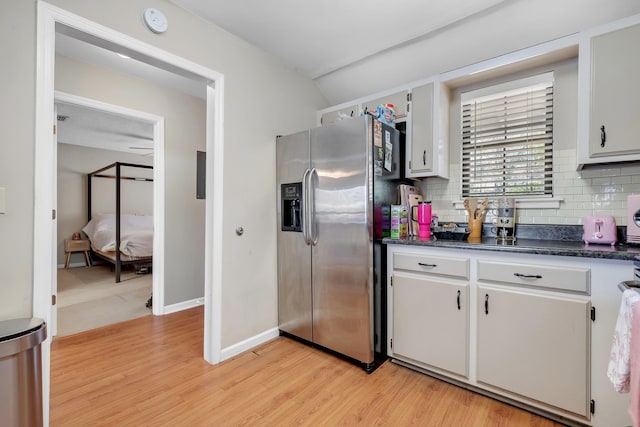 kitchen with white cabinets, light hardwood / wood-style floors, stainless steel fridge, and decorative backsplash