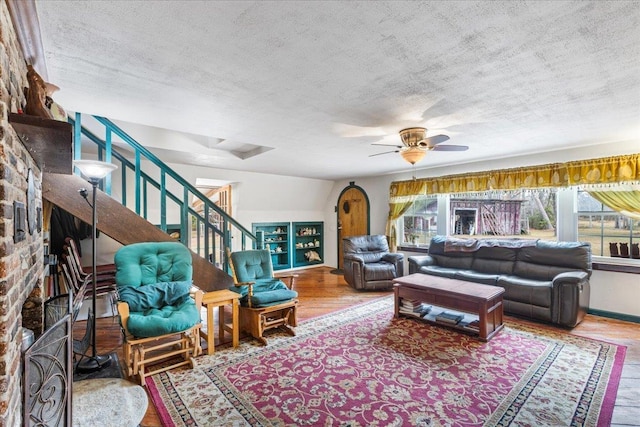 living room with ceiling fan, wood-type flooring, and a textured ceiling