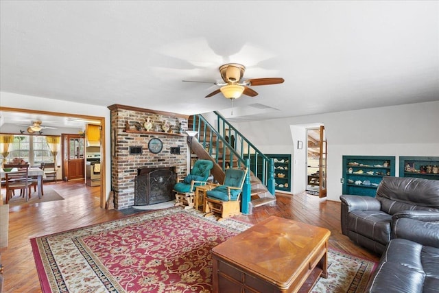 living room featuring hardwood / wood-style flooring, ceiling fan, and a brick fireplace