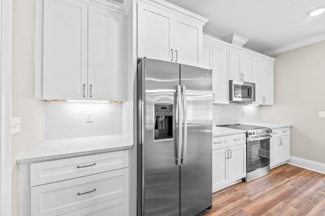 kitchen featuring appliances with stainless steel finishes, light wood-type flooring, white cabinetry, and crown molding