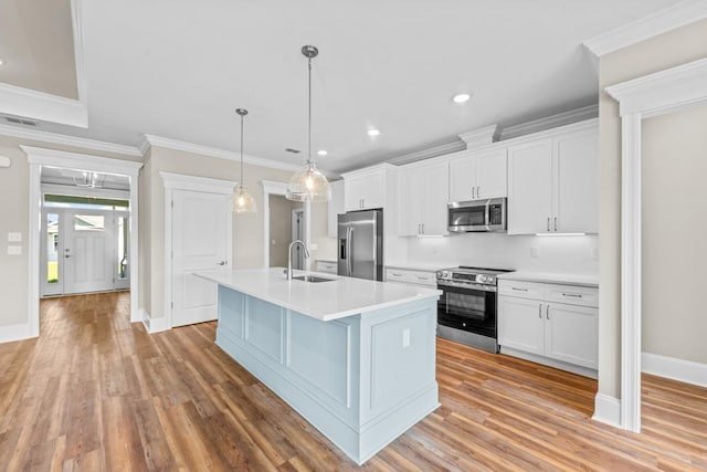 kitchen featuring white cabinets, a center island with sink, stainless steel appliances, and hanging light fixtures