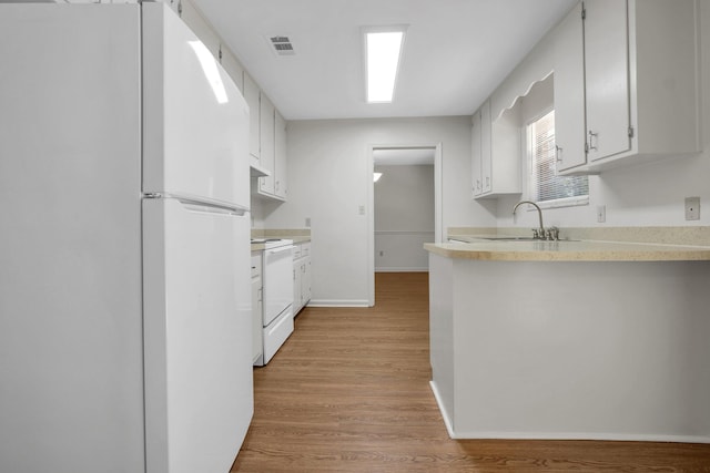 5804 Old Forge Ct, Tallahassee, FL 32317 - kitchen with white appliances, light wood-type flooring, light countertops, white cabinets, and a peninsula