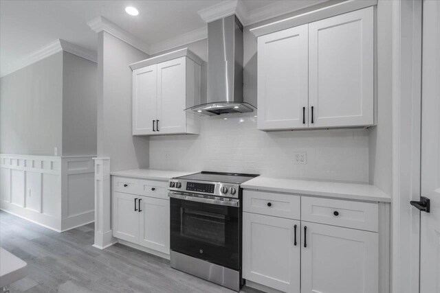 10096 Green Fountain Rd, Tallahassee, FL 32305 - kitchen with stainless steel electric range oven, wall chimney exhaust hood, ornamental molding, light wood-style flooring, and white cabinets