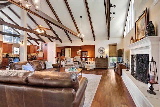 living room with beam ceiling, ceiling fan with notable chandelier, dark wood-style flooring, and a towering ceiling