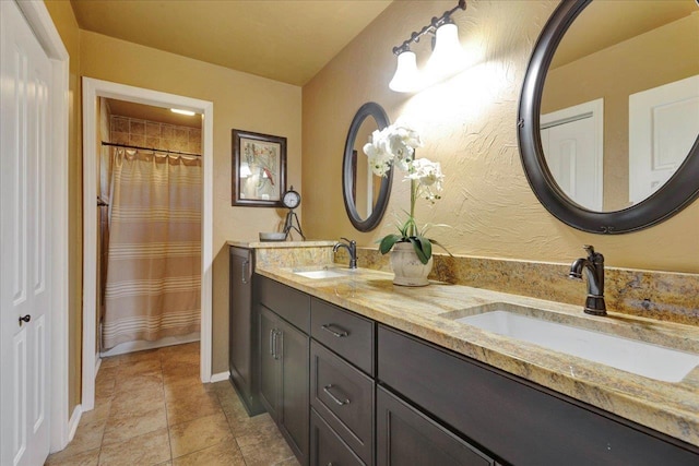 full bath featuring double vanity, baseboards, tile patterned floors, and a sink