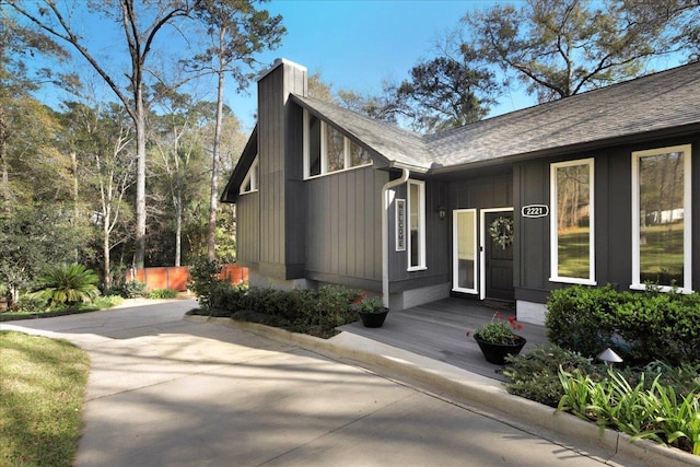 exterior space with roof with shingles and a chimney