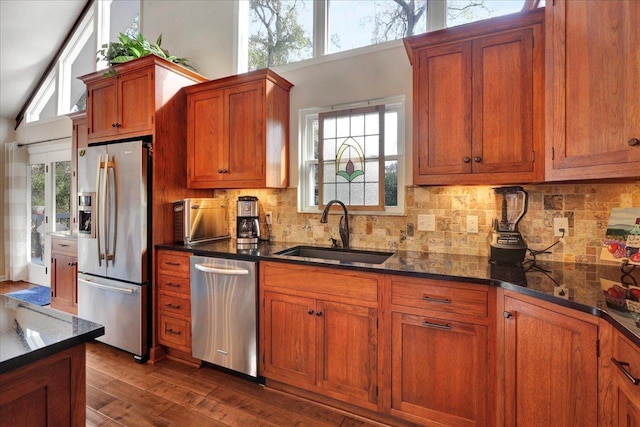 kitchen featuring brown cabinets, appliances with stainless steel finishes, dark wood-style floors, plenty of natural light, and a sink