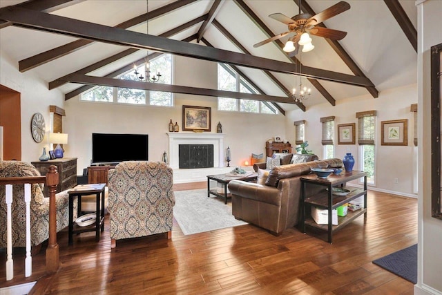 living area featuring ceiling fan with notable chandelier, wood finished floors, a fireplace with raised hearth, and high vaulted ceiling